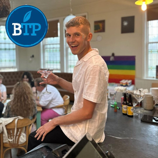 People inside Boston Tea Party with a pride flag on the wall