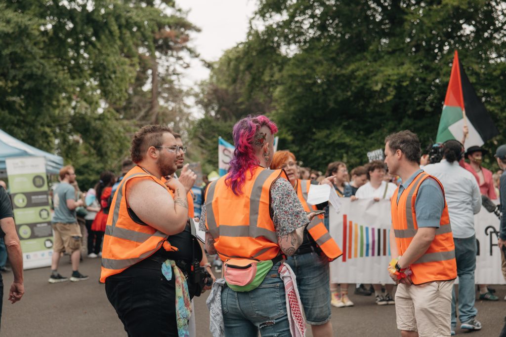 five volunteers meeting at the start of the march for Bath Pride 2025