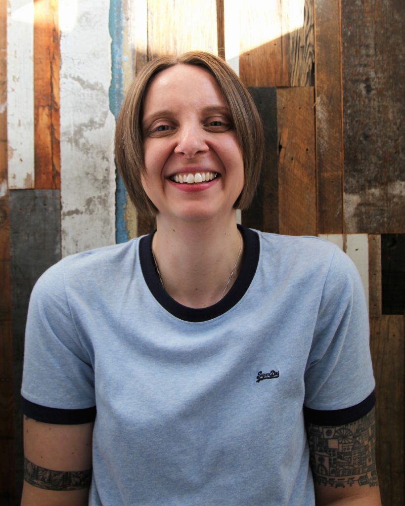 a smiling Jo in front of a wooden backdrop